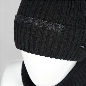 Close-up of black cable-knit hat and scarf set with fleece lining and woven logo tag