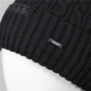 Detail of black knit beanie showing cable patterns and CULEN brand tag on thick fabric