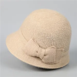 Détail d'un chapeau cloche en tricot beige montrant la texture douce et le nœud latéral