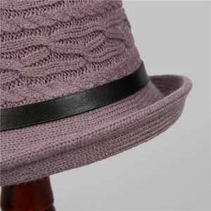 Close-up of purple knit bucket hat showing cable weave and black leather strap detail