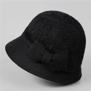 Détail d'un chapeau cloche noir en fausse fourrure avec un grand nœud décoratif sur le côté
