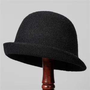 Détail du chapeau cloche en feutre de laine noir avec bord roulé sur un support