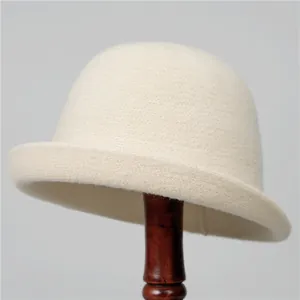 Détail d'un chapeau cloche en tricot crème sur un support en bois avec un bord naturel
