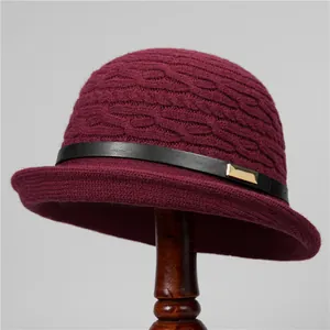 Close-up of wine red knit bucket hat featuring a black leather band and gold metal buckle
