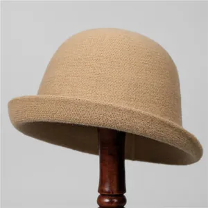 Détail d'un chapeau cloche en tricot camel avec bord roulé sur un support en bois