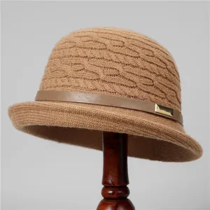Detail of cable knit wool bucket hat with leather strap and gold buckle on a stand