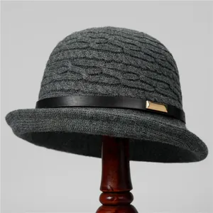Close-up of gray knit cloche hat with textured diamond pattern and black leather buckle strap