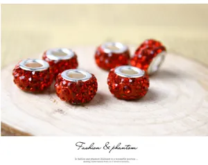 Close-up of six red crystal paved alloy spacer beads on a decorative wooden tray