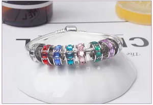 Dettaglio di un braccialetto a serpente d'argento con sette perle di zircone colorate