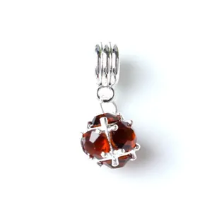 Detail of DIY bead charm with faceted reddish-brown crystal and silver cross-shaped metal cage
