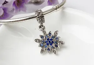 Makroaufnahme von Schneeflocken-Charm mit blauen Steinen auf Schlangenarmband