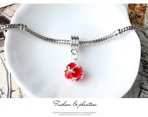 Macro shot of silver snake chain bracelet with a faceted red crystal pendant charm