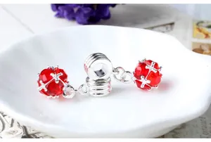 Macro detail of red zircon charm with silver cross cage for DIY bracelet jewelry