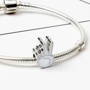 Macro dettaglio del bracciale snake con ciondolo a mano in smalto bianco segno V