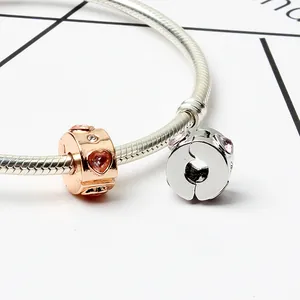 Macro shot of rose gold heart charm with pink stones and silver snake chain bracelet