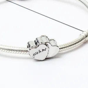 Detalle macro de colgante de corazón plateado con grabado you & me en pulsera de cadena
