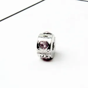 Macro shot of silver charm with pink heart crystals and round zirconia for DIY bracelets