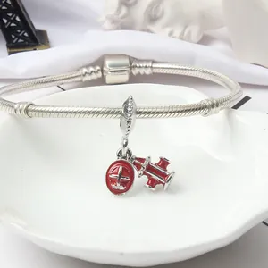 Silver snake chain bracelet featuring red airplane and hydrant charms in a shell tray