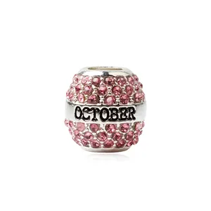 Détail macro d'une perle charm en alliage argenté avec strass roses et gravure Octobre
