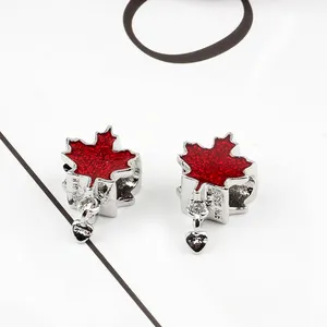 Close-up of red maple leaf charms with heart pendants and silver enamel finish