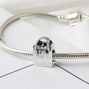 Retro silver handbag charm with bow relief on snake chain bracelet, white background