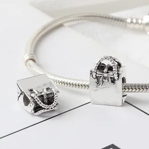 Macro shot of retro silver handbag charms with bow details on a snake chain bracelet