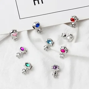 Close-up of DIY robot astronaut charms with colorful gemstones for jewelry making