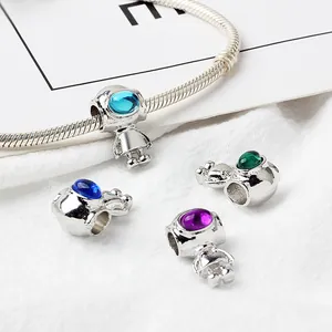 Detailed close-up of astronaut jewelry charms with colorful visors on a silver snake chain