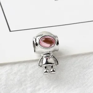 Macro view of silver astronaut charm with pink gemstone detail for DIY jewelry