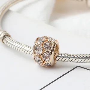 Detalle de un dije dorado con cristales brillantes en una pulsera de cadena de serpiente plateada