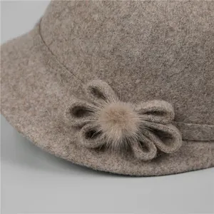 Détail d'un chapeau en laine montrant la fleur décorative et la texture du pompon