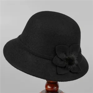 Detailed view of black wool cloche hat featuring a decorative 3D flower with pompom