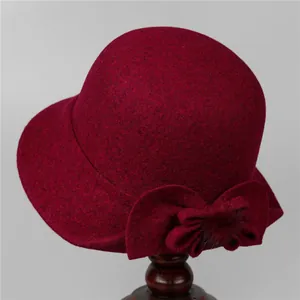 Detailed view of wine red wool cloche hat with a large bow and soft fur ball accents