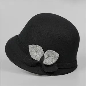 Dettaglio del cappello cloche in lana nera con foglia decorativa e trama morbida