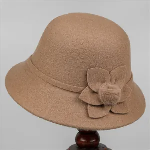 Detailed view of camel wool bucket hat with decorative fabric flower and soft fur pompom