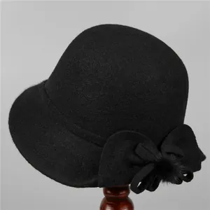 Detail of elegant black wool cloche hat for elderly women with bow and plush pom-pom