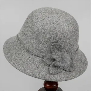 Detail of wool felt bucket hat featuring handmade flower and soft fur pompom decoration