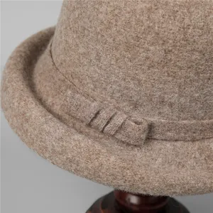 French vintage camel wool felt cloche hat with a bow accent on a wooden display stand