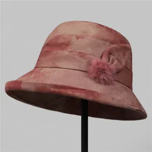 Detail of pink tie-dye bucket hat featuring a fabric bow and plush faux fur pom-pom decor