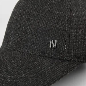 Macro shot of dark grey wool blend cap fabric texture and metallic N logo detail