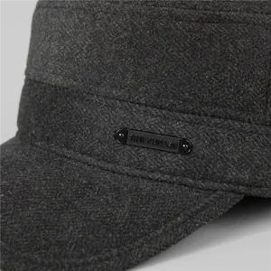 Close-up van de grijze wollen stof en metalen logoplaat op de winterse platte pet
