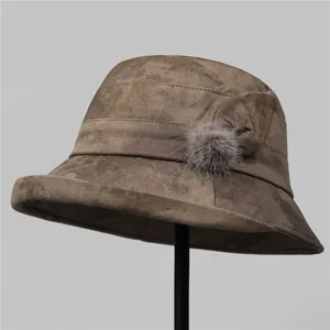 Detail view of brown marble texture felt bucket hat with bow and soft fur pom-pom detail