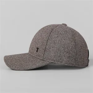 Dettaglio del berretto in tweed con paraorecchie, trama e decorazione a T in metallo
