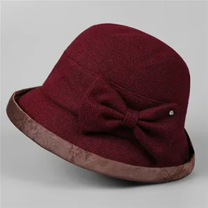 Close-up of wine red cloche hat featuring textured fabric and a delicate bow with rhinestone