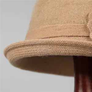 Close-up of camel knit wool hat showing fine texture and decorative strap detail