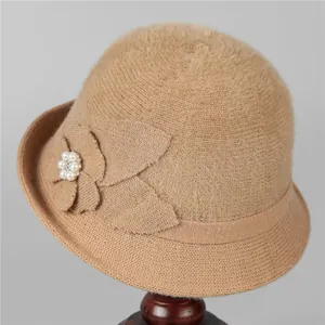 Detailed texture of khaki knitted winter hat with decorative fabric flower and pearls