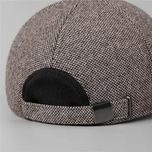 Dettaglio del tessuto tweed grigio e della fibbia metallica regolabile sul berretto