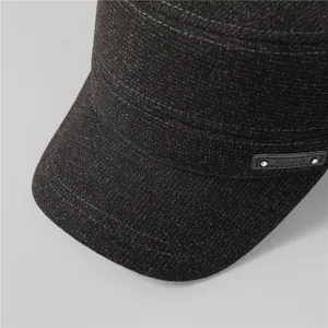 Detailed close-up of dark grey wool texture and metal fashion label on winter flat top cap