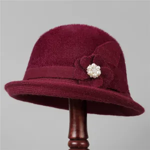Detail of burgundy knitted bucket hat showing floral applique with pearl and rhinestone
