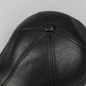Detailed close-up of premium black leather cap top with reinforced stitching and button